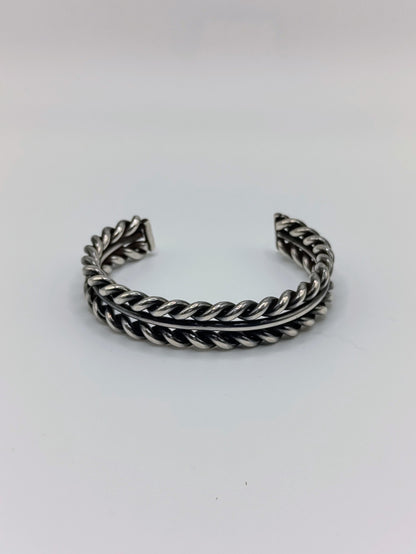 Front view of heavy sterling silver braided rope cuff bracelet with smooth center band, open-ended, on white background.