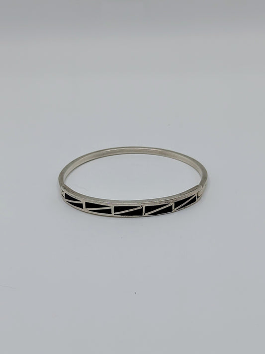 Vintage Mexican sterling silver onyx inlay hinged bangle bracelet with geometric black triangle pattern on a white background