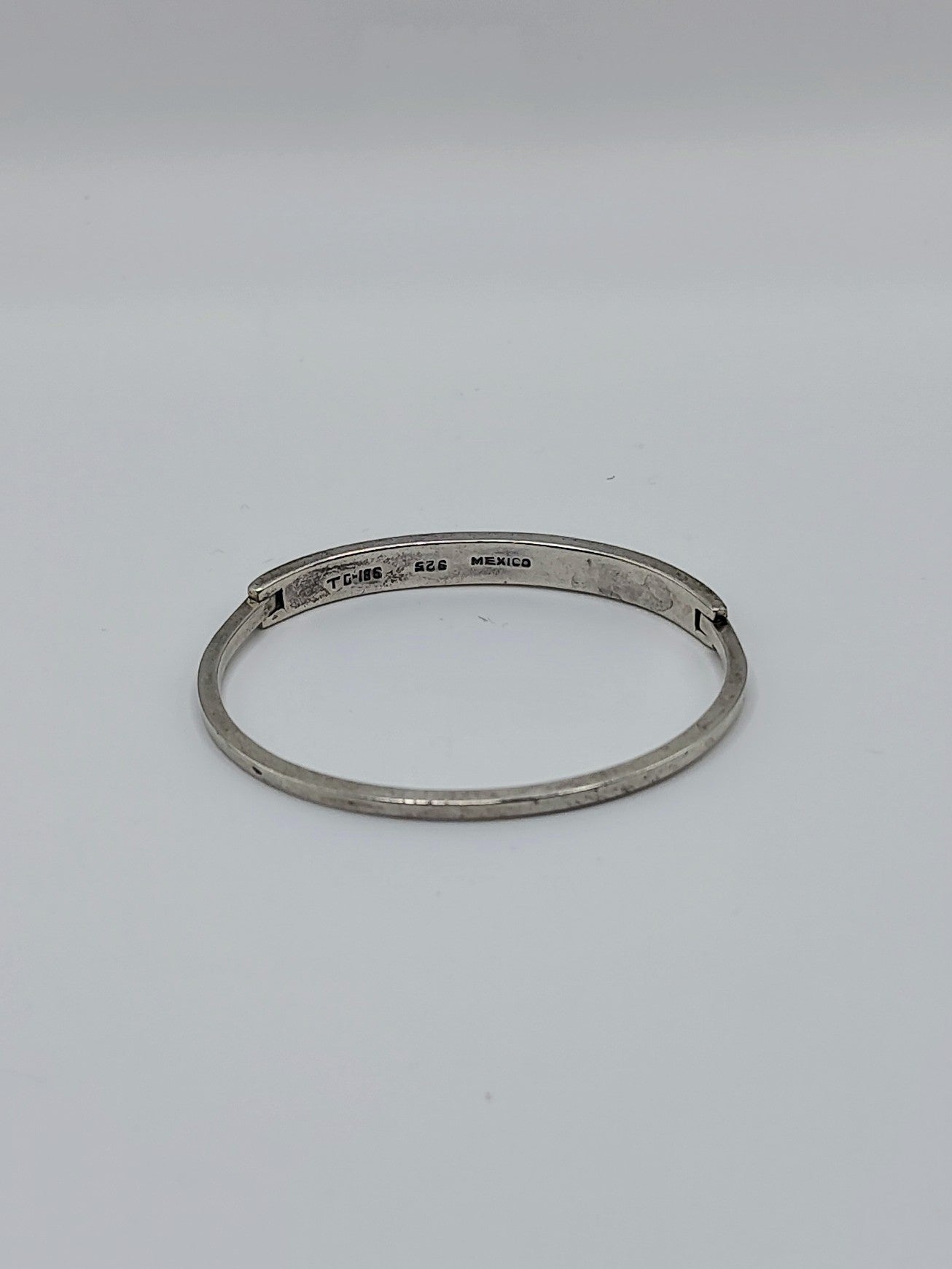 Vintage Mexican sterling silver onyx inlay hinged bangle bracelet with geometric black triangle pattern on a white background