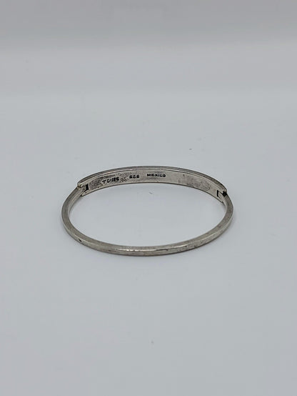 Vintage Mexican sterling silver onyx inlay hinged bangle bracelet with geometric black triangle pattern on a white background