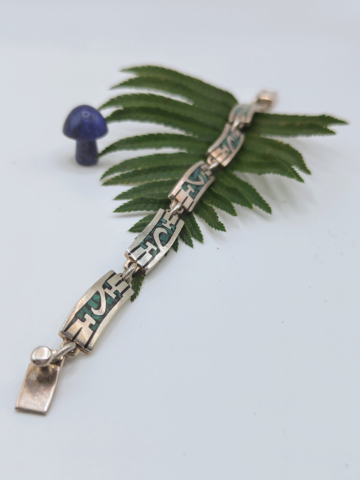 Overhead view of a vintage Mexican sterling silver bracelet with green malachite inlay panels in a geometric