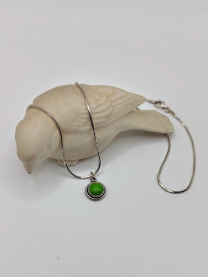 Verdant Peace Necklace with green turquoise pendant draped over a small white bird figurine.