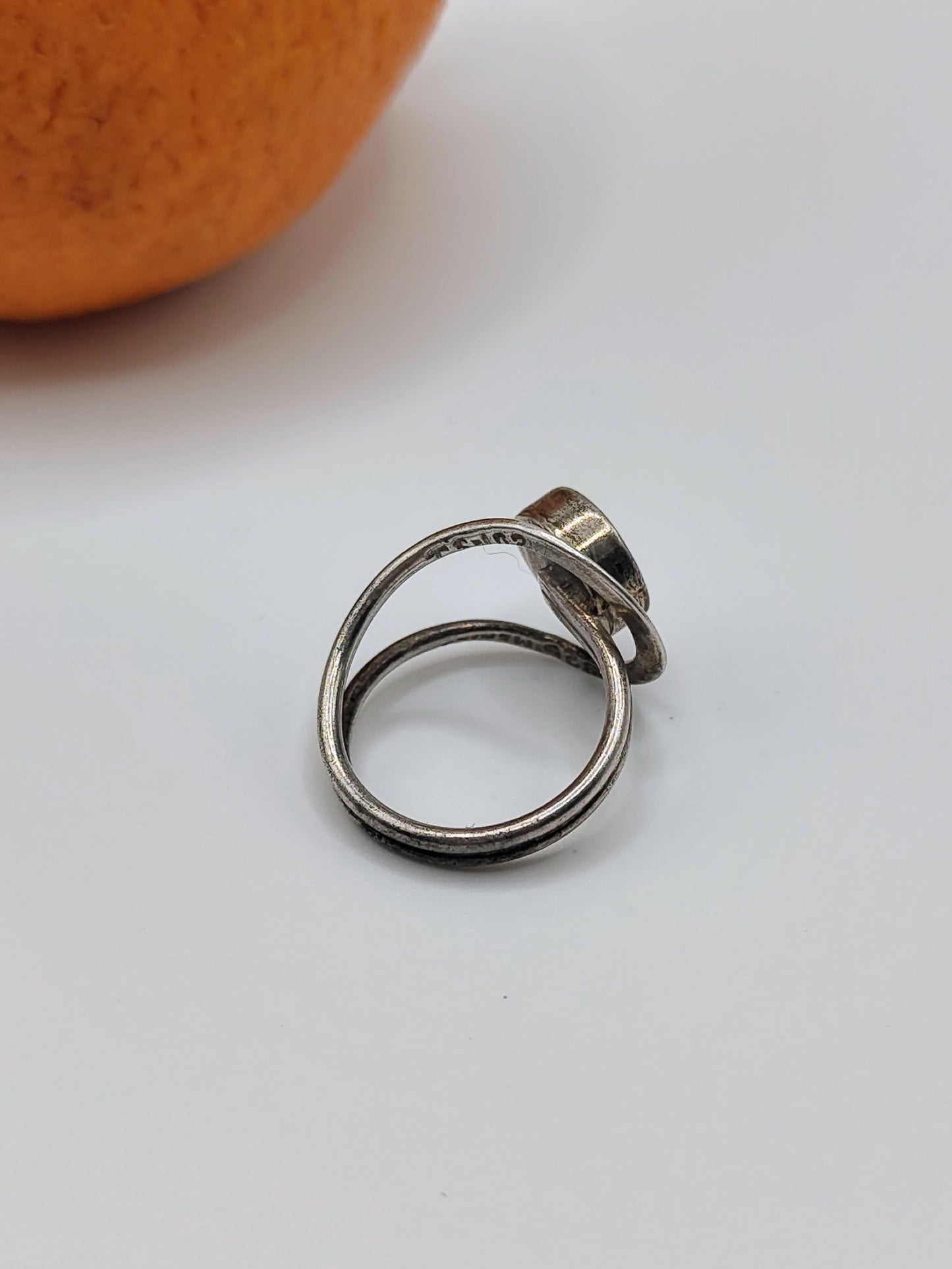 An Onyx Ring, a vintage Mexican sterling silver ring with round black onyx cabochon and looping double band, on an orange.