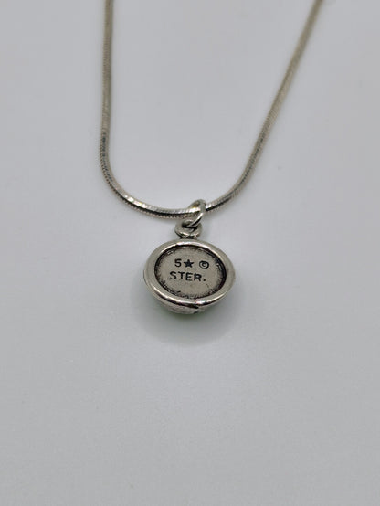 Back view of round sterling silver pendant showing “5★ STAR.” hallmark on the reverse, hanging from a silver chain.