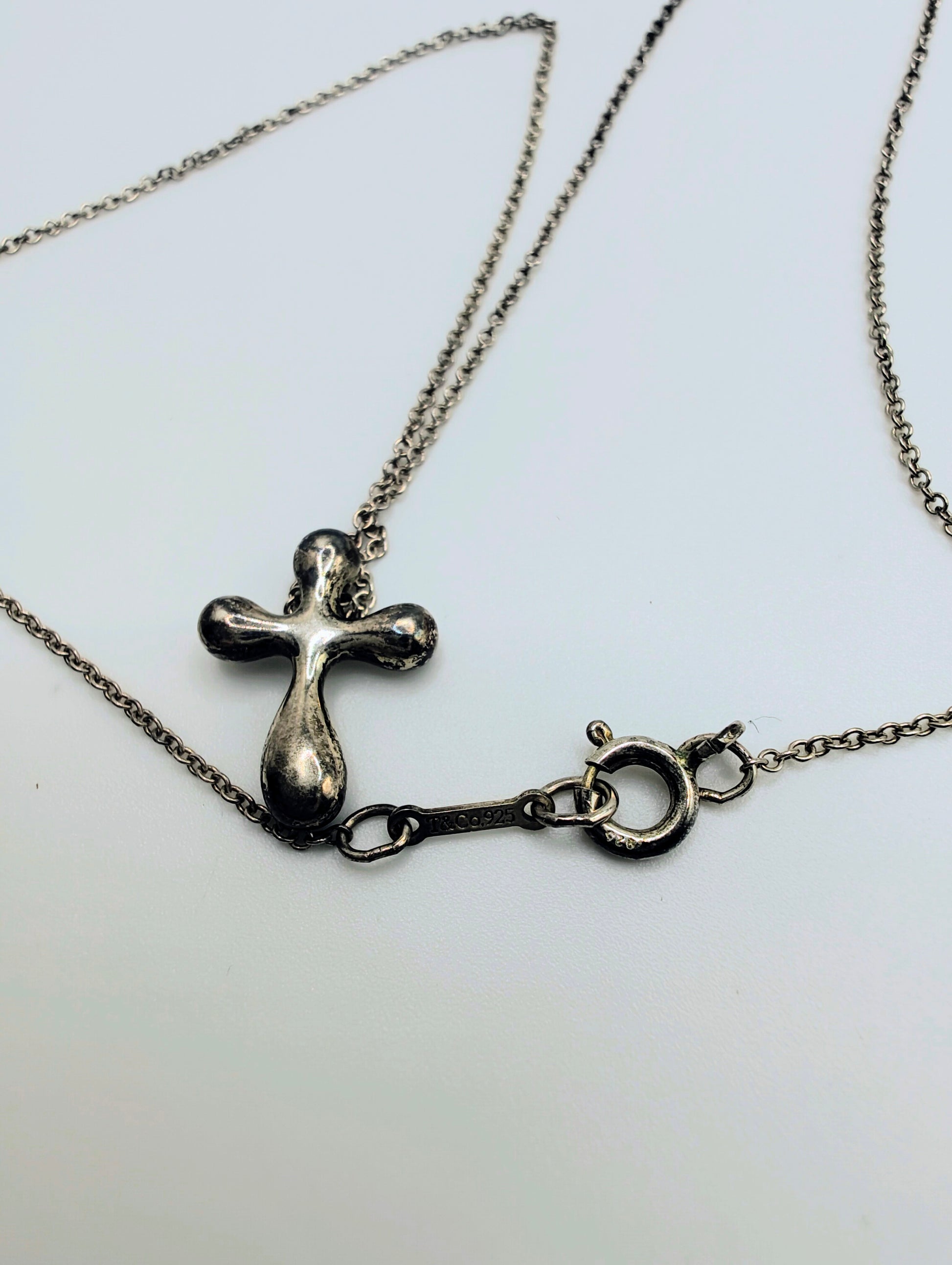 Sterling silver Tiffany & Co. Elsa Peretti teardrop cross pendant hanging from a delicate silver chain.