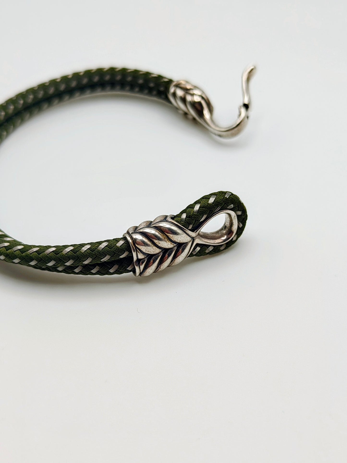 Dark forest-green braided cord bracelet with sculpted sterling silver end caps and a hook clasp, designed by David Yurman.