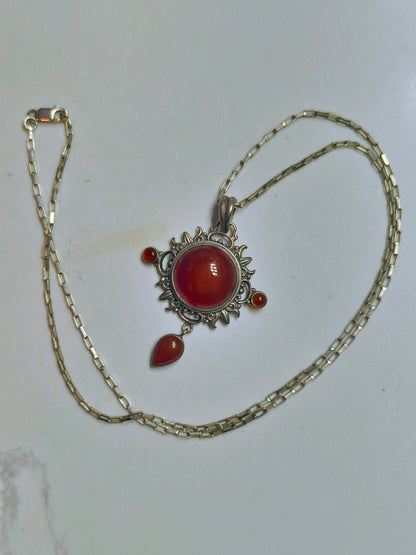 Sterling silver pendant necklace with a domed carnelian stone, two small side carnelian cabochons, and a dangling teardrop