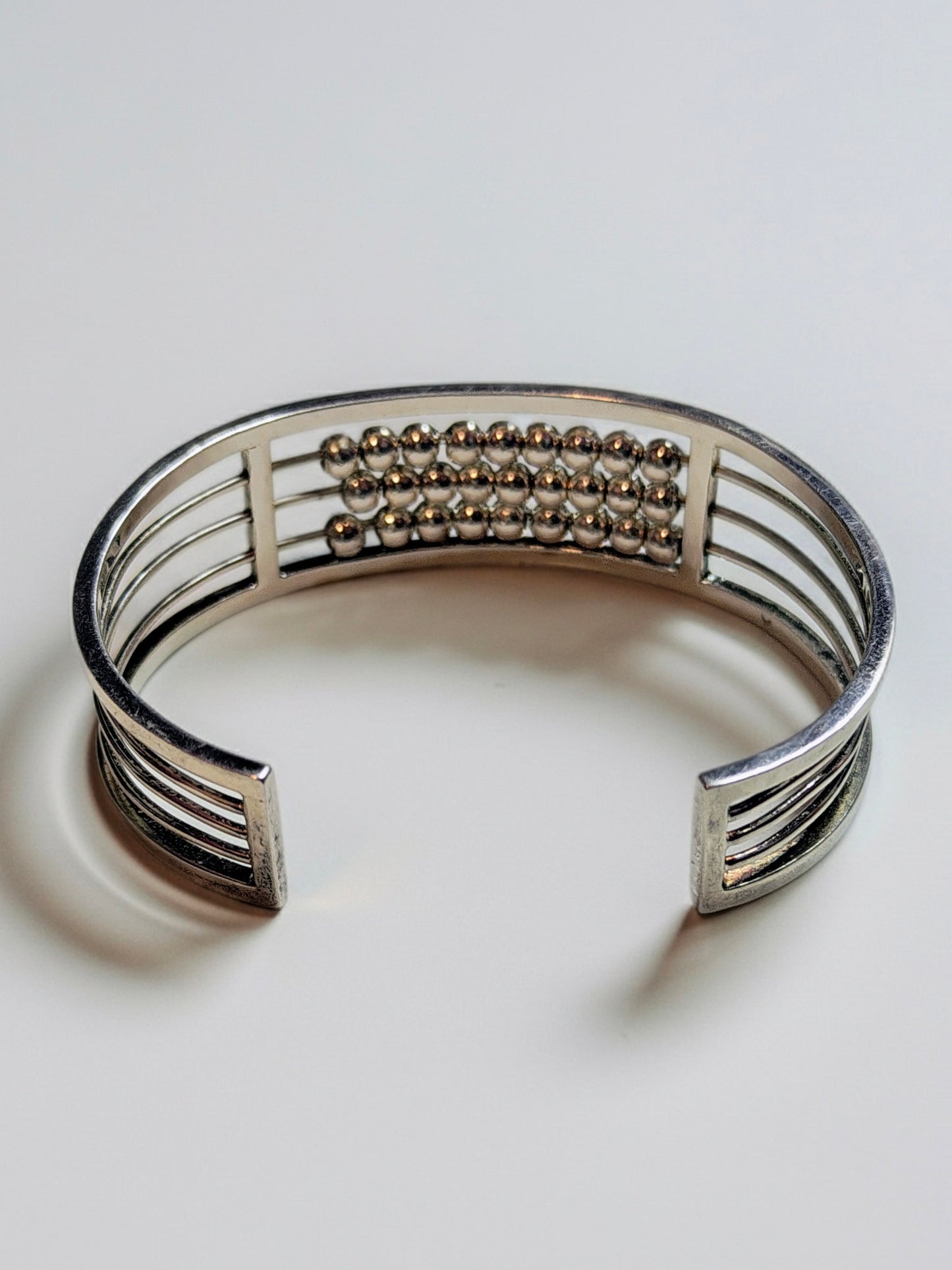 Sterling silver Abacus of Thresholds cuff bracelet with rows of movable silver beads on parallel bars.