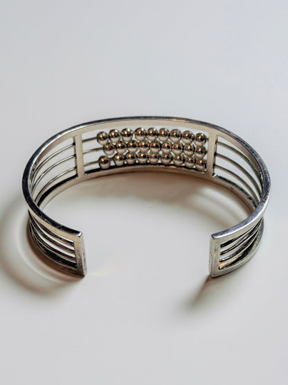 Sterling silver Abacus of Thresholds cuff bracelet with rows of movable silver beads on parallel bars.
