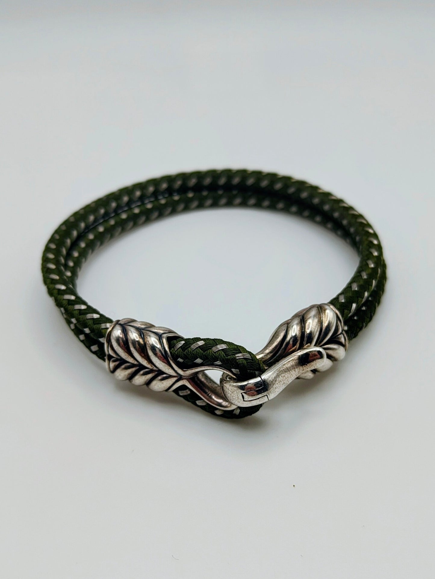 Dark forest-green braided cord bracelet with sculpted sterling silver end caps and a hook clasp, designed by David Yurman.