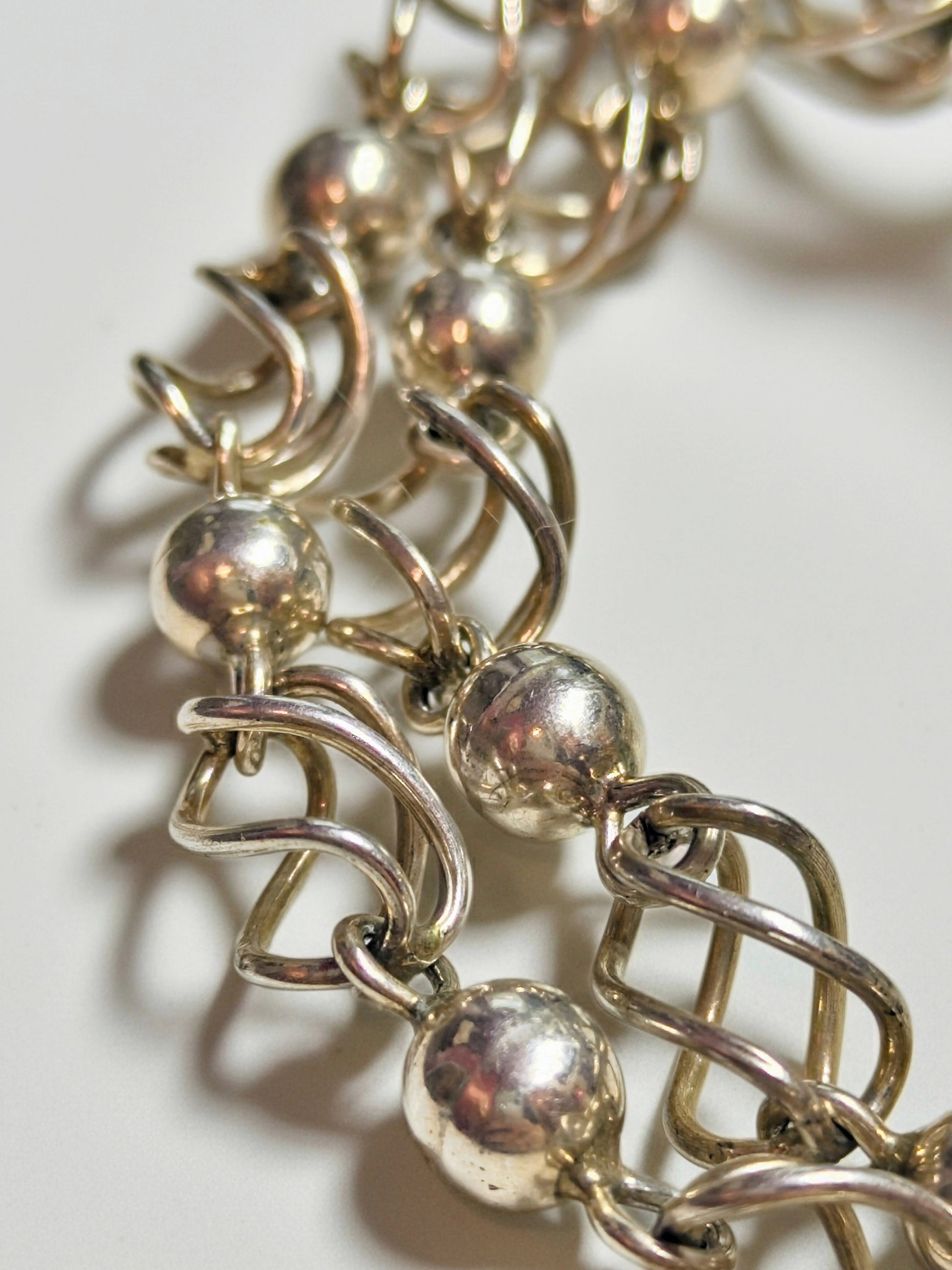 Sterling silver necklace composed of polished round beads alternating with open spiral-cage links.