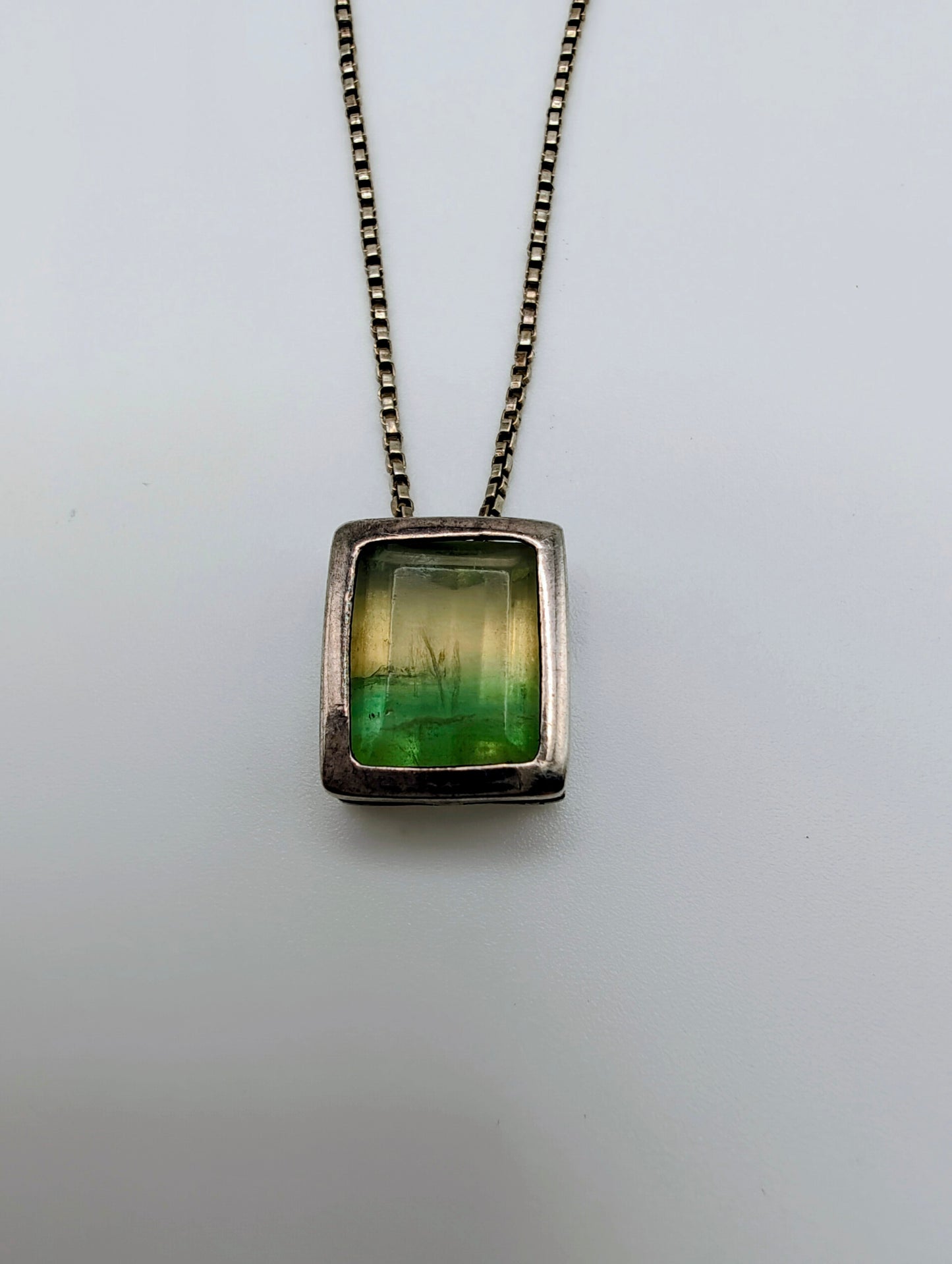 Sterling silver necklace featuring a rectangular bezel-set fluorite stone that fades from honey yellow to mossy green, hanging from an 18-inch box chain