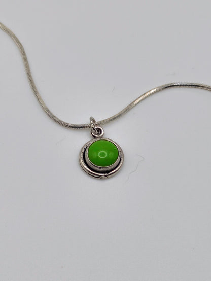 Sterling silver necklace with small round bezel-set green turquoise cabochon pendant on a snake-style chain.