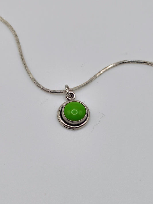 Sterling silver necklace with small round bezel-set green turquoise cabochon pendant on a snake-style chain.
