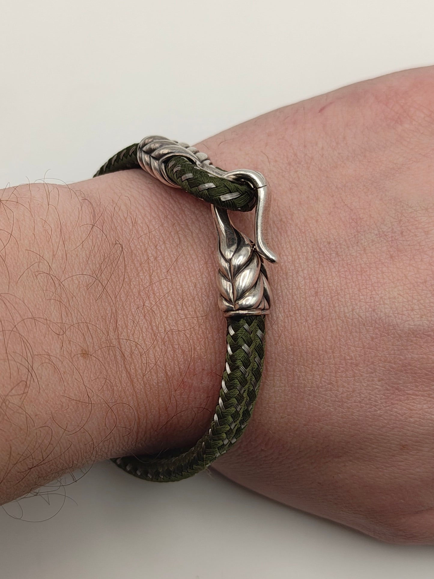 Dark forest-green braided cord bracelet with sculpted sterling silver end caps and a hook clasp, designed by David Yurman.