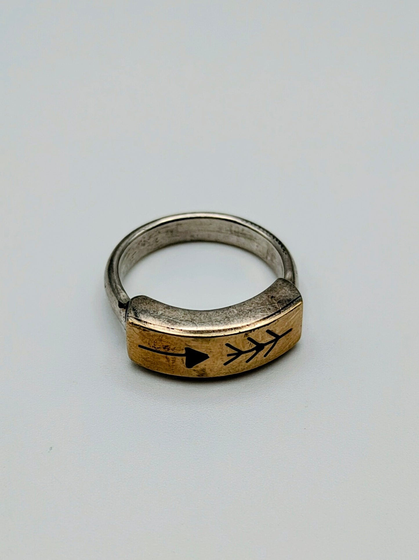 Sterling silver and 14k gold ring featuring an engraved arrow and feather design, with a white background.