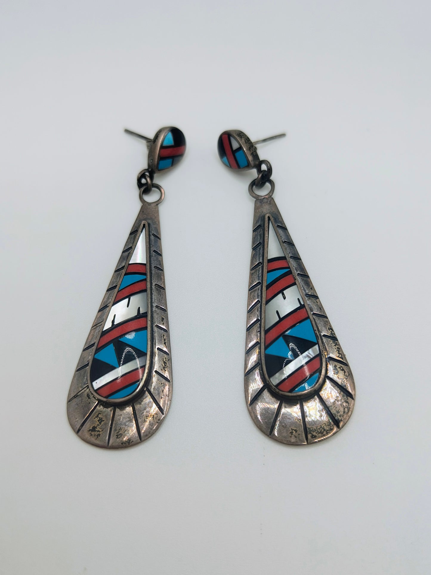 Pair of long sterling silver teardrop dangle earrings with geometric inlay of turquoise, coral, onyx, and mother-of-pearl.