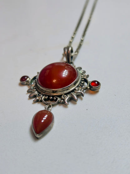 Sterling silver pendant necklace with a domed carnelian stone, two small side carnelian cabochons, and a dangling teardrop