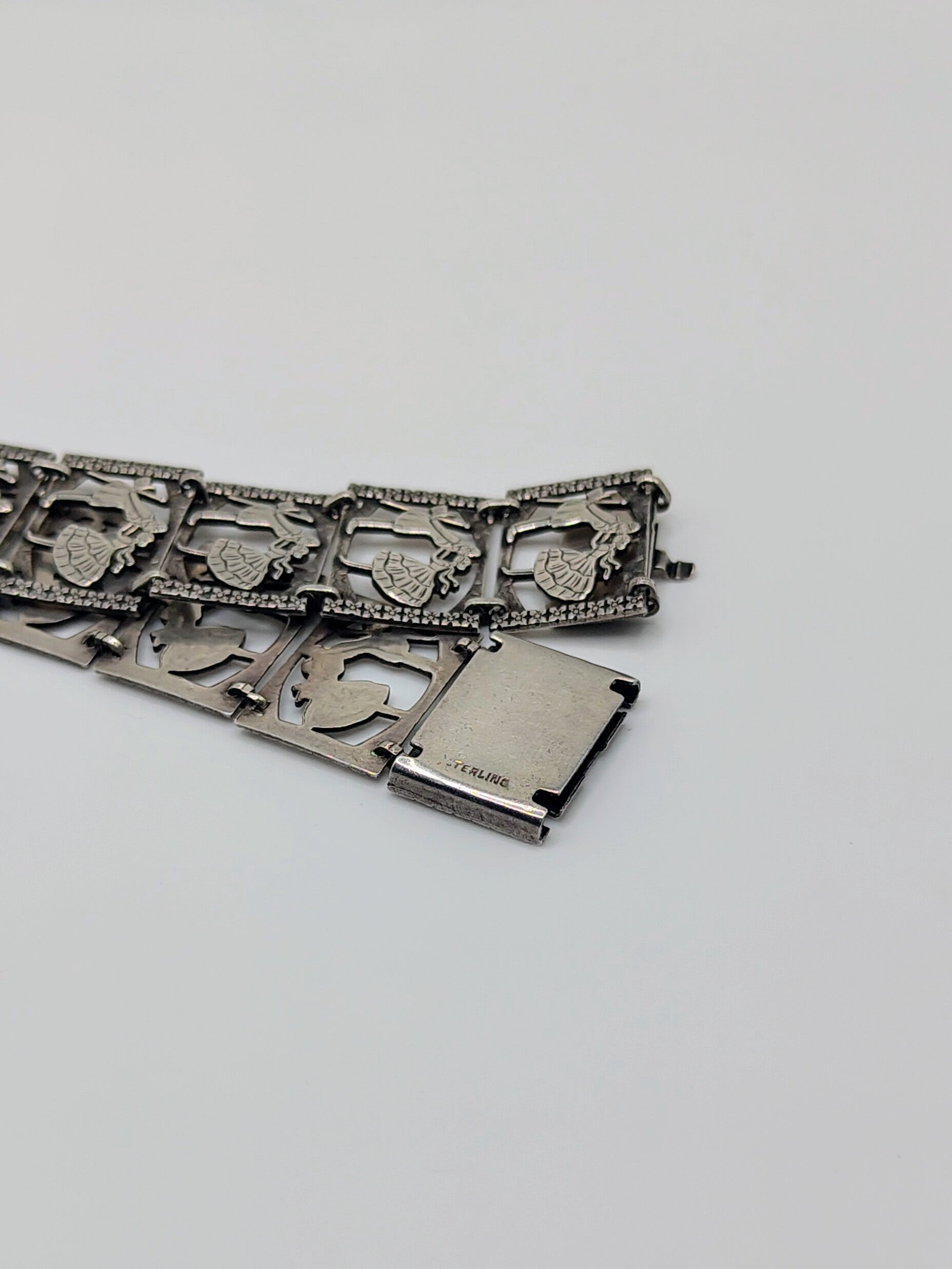 Sterling silver panel bracelet with raised dancing couple designs.