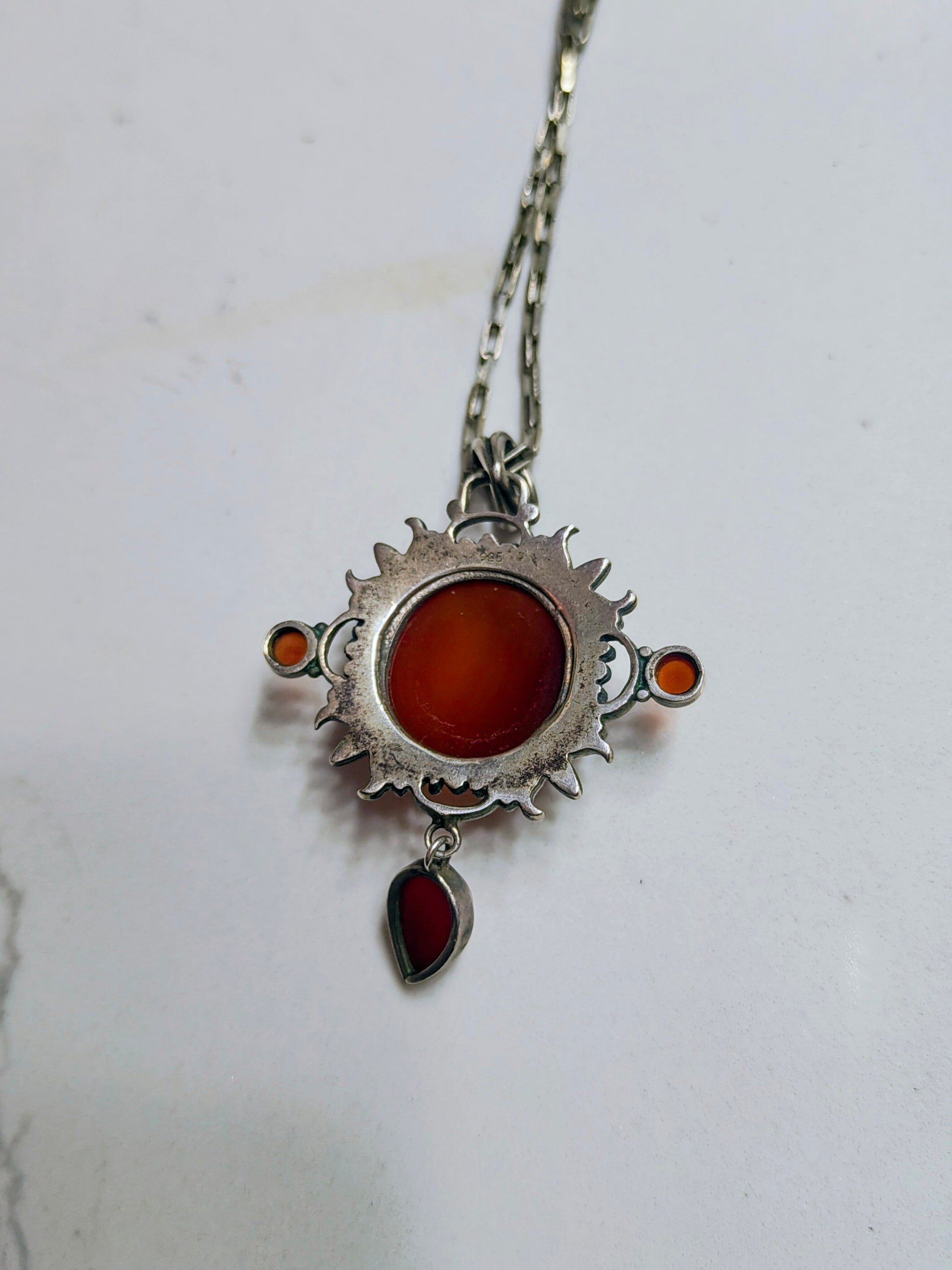 Sterling silver pendant necklace with a domed carnelian stone, two small side carnelian cabochons, and a dangling teardrop