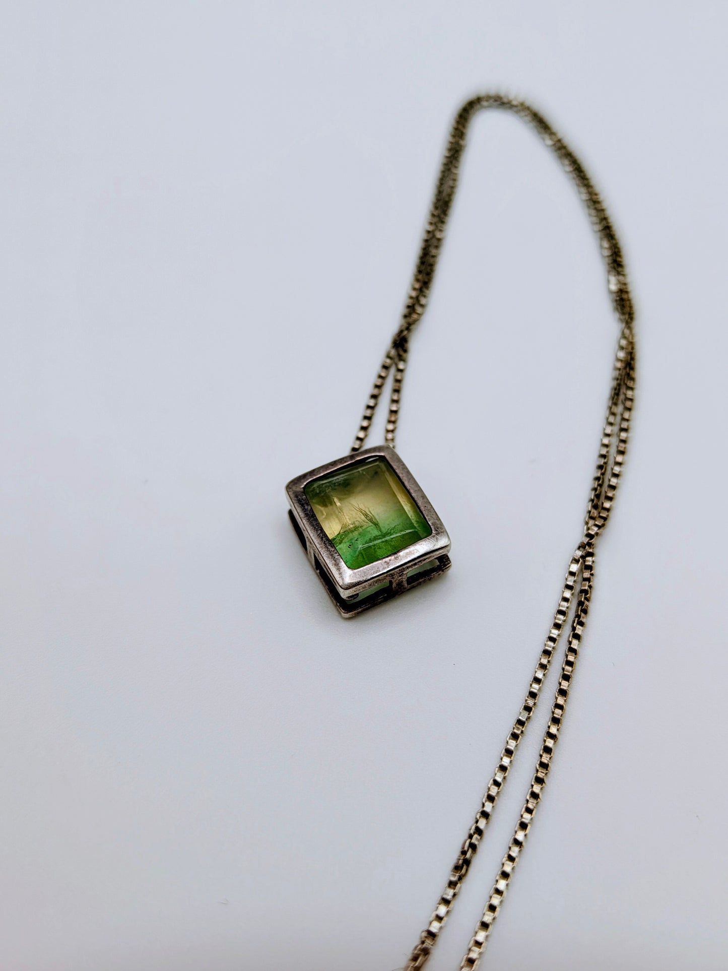 Sterling silver necklace featuring a rectangular bezel-set fluorite stone that fades from honey yellow to mossy green, hanging from an 18-inch box chain