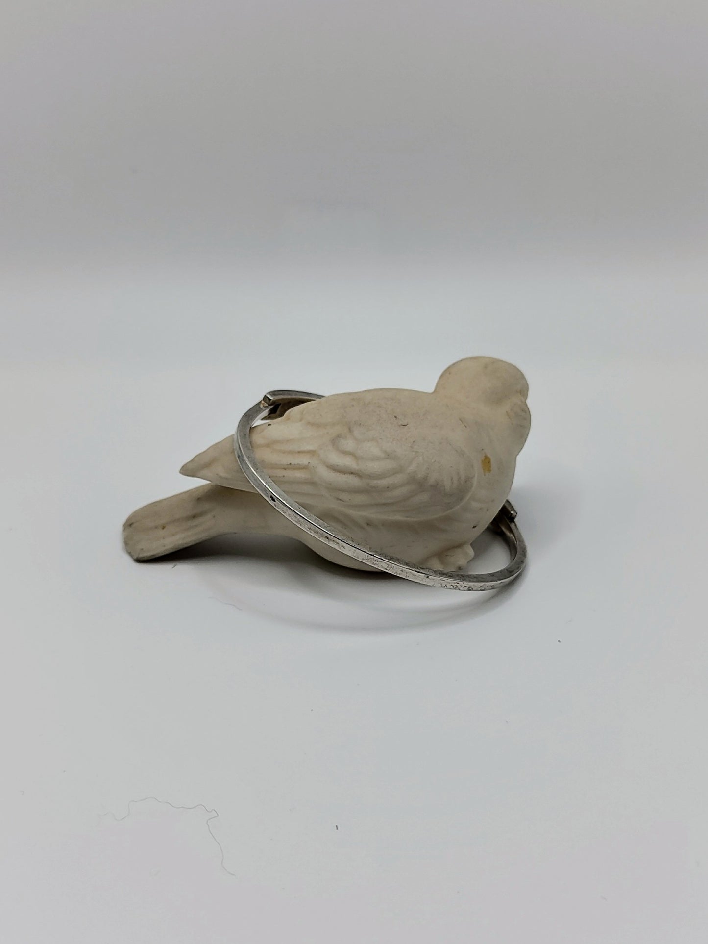 Vintage sterling silver onyx inlay bangle bracelet resting around a white bird figurine on a clean white background.