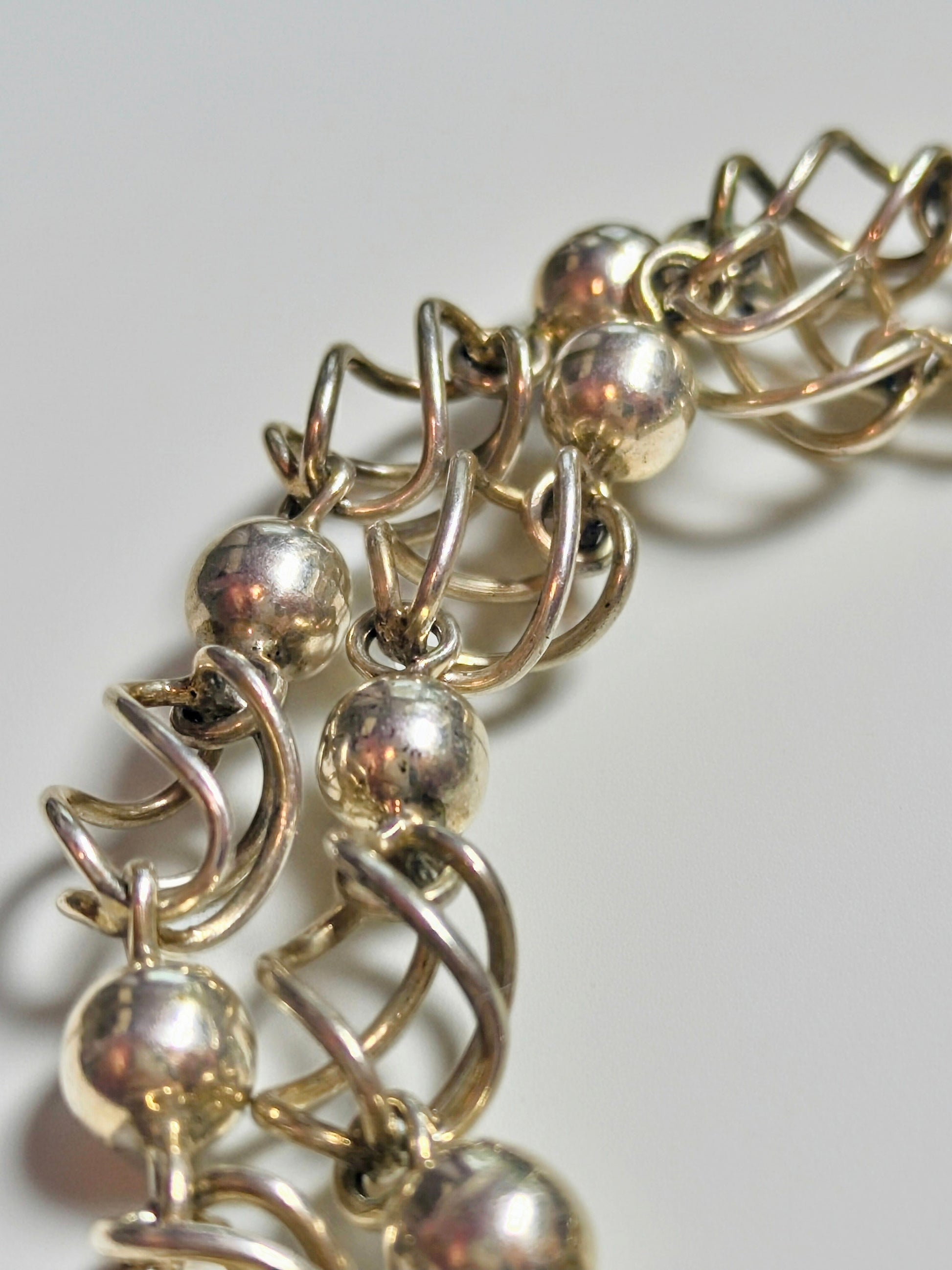 Sterling silver necklace composed of polished round beads alternating with open spiral-cage links.
