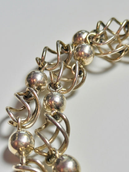 Sterling silver necklace composed of polished round beads alternating with open spiral-cage links.