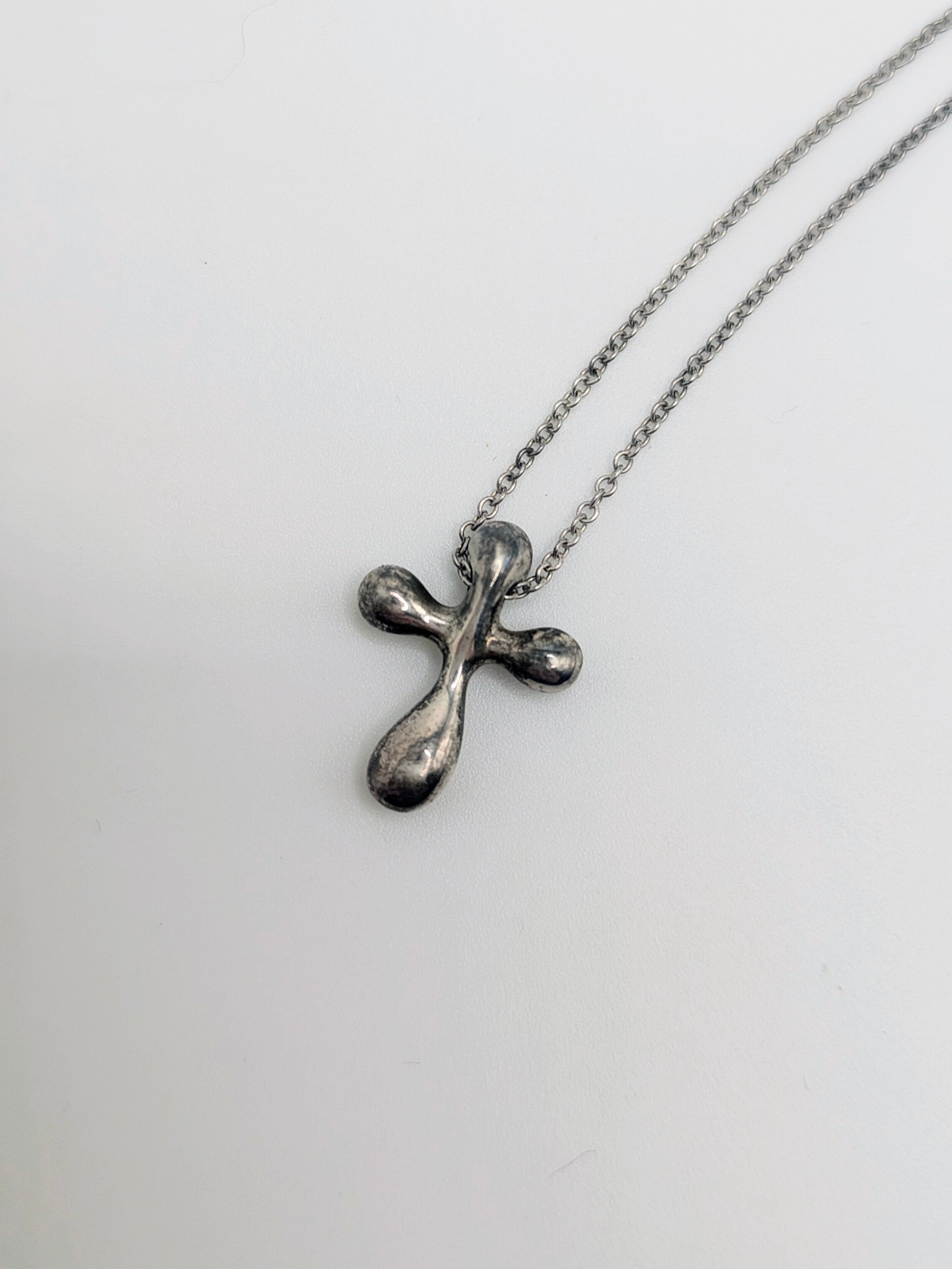 Sterling silver Tiffany & Co. Elsa Peretti teardrop cross pendant hanging from a delicate silver chain.