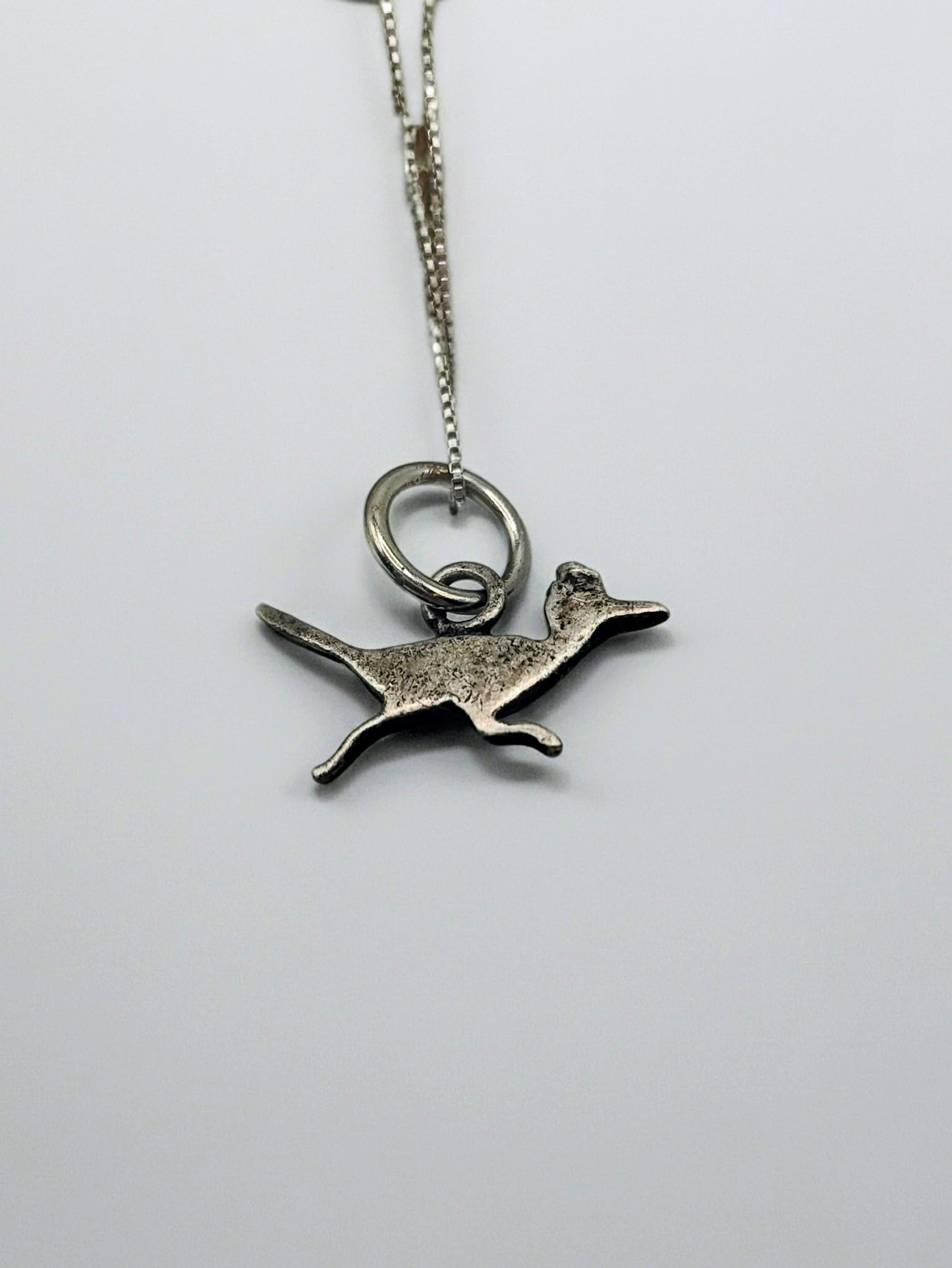 Back view of sterling silver roadrunner pendant on an 18 inch box chain, showing the simple textured silhouette