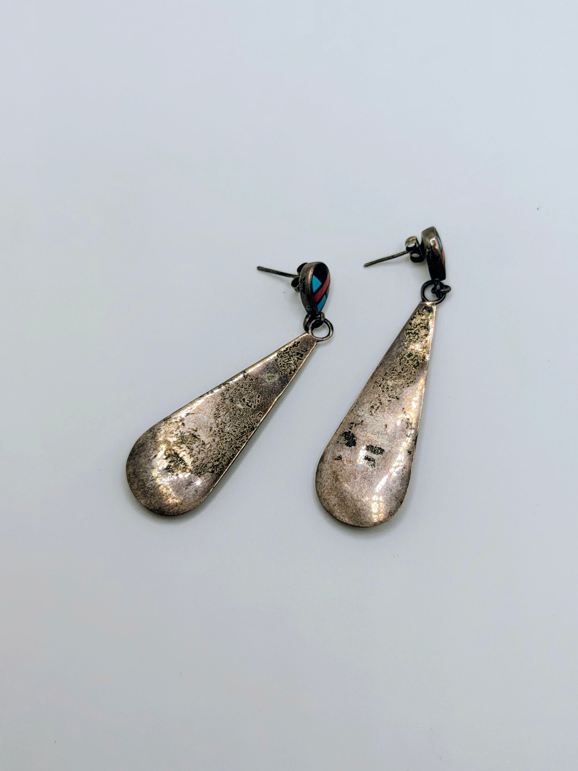Pair of long sterling silver teardrop dangle earrings with geometric inlay of turquoise, coral, onyx, and mother-of-pearl.