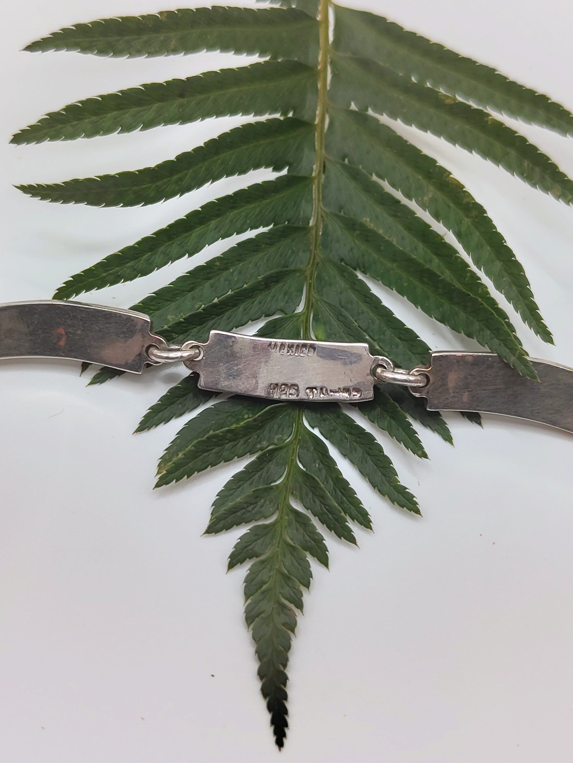 Overhead view of a vintage Mexican sterling silver bracelet with green malachite inlay panels in a geometric