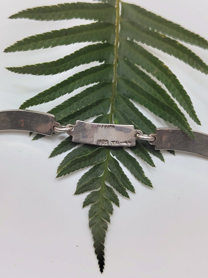 Overhead view of a vintage Mexican sterling silver bracelet with green malachite inlay panels in a geometric