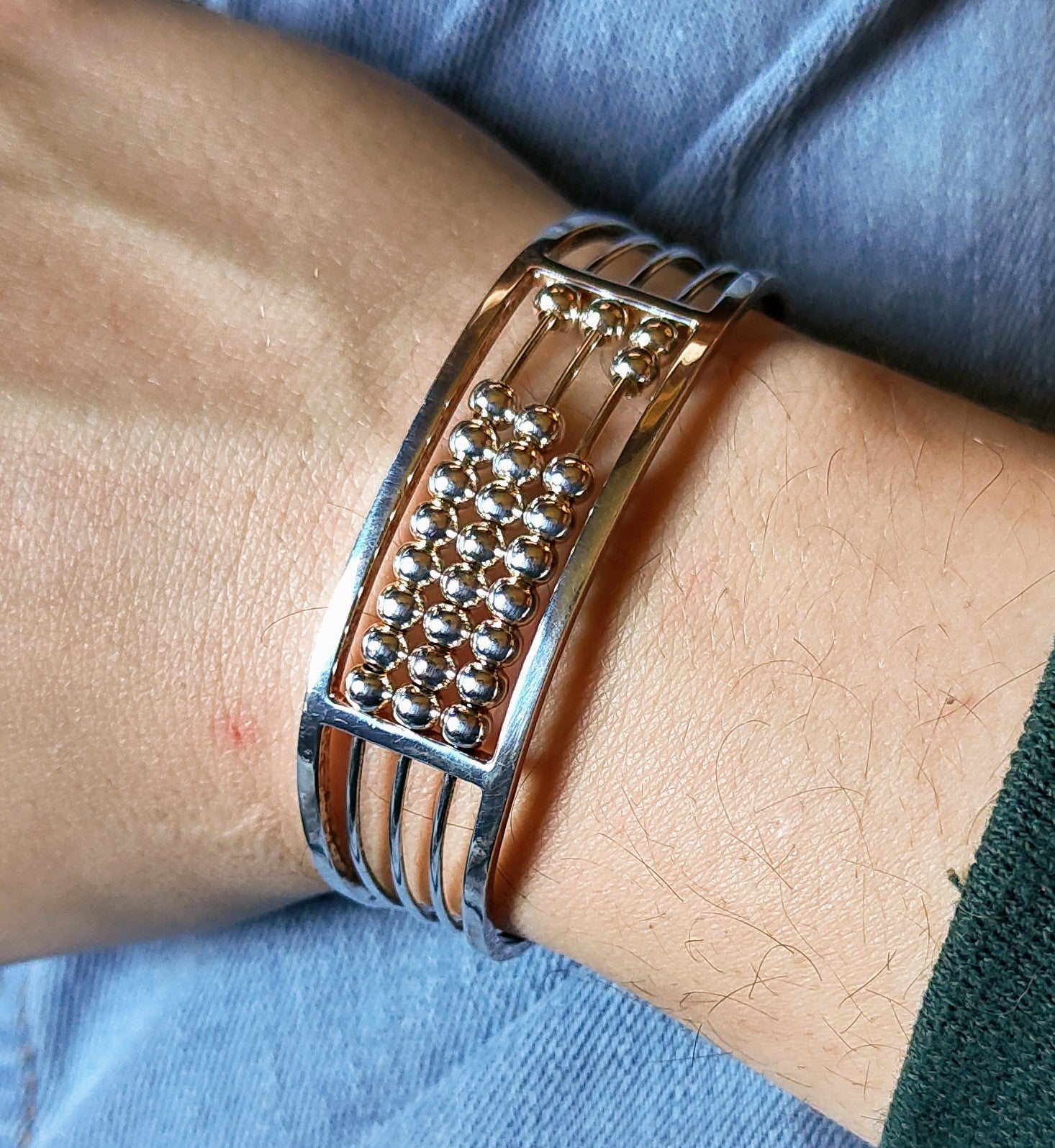 Abacus of Thresholds silver bead cuff bracelet worn on a wrist, showing the central cluster of round beads against denim.
