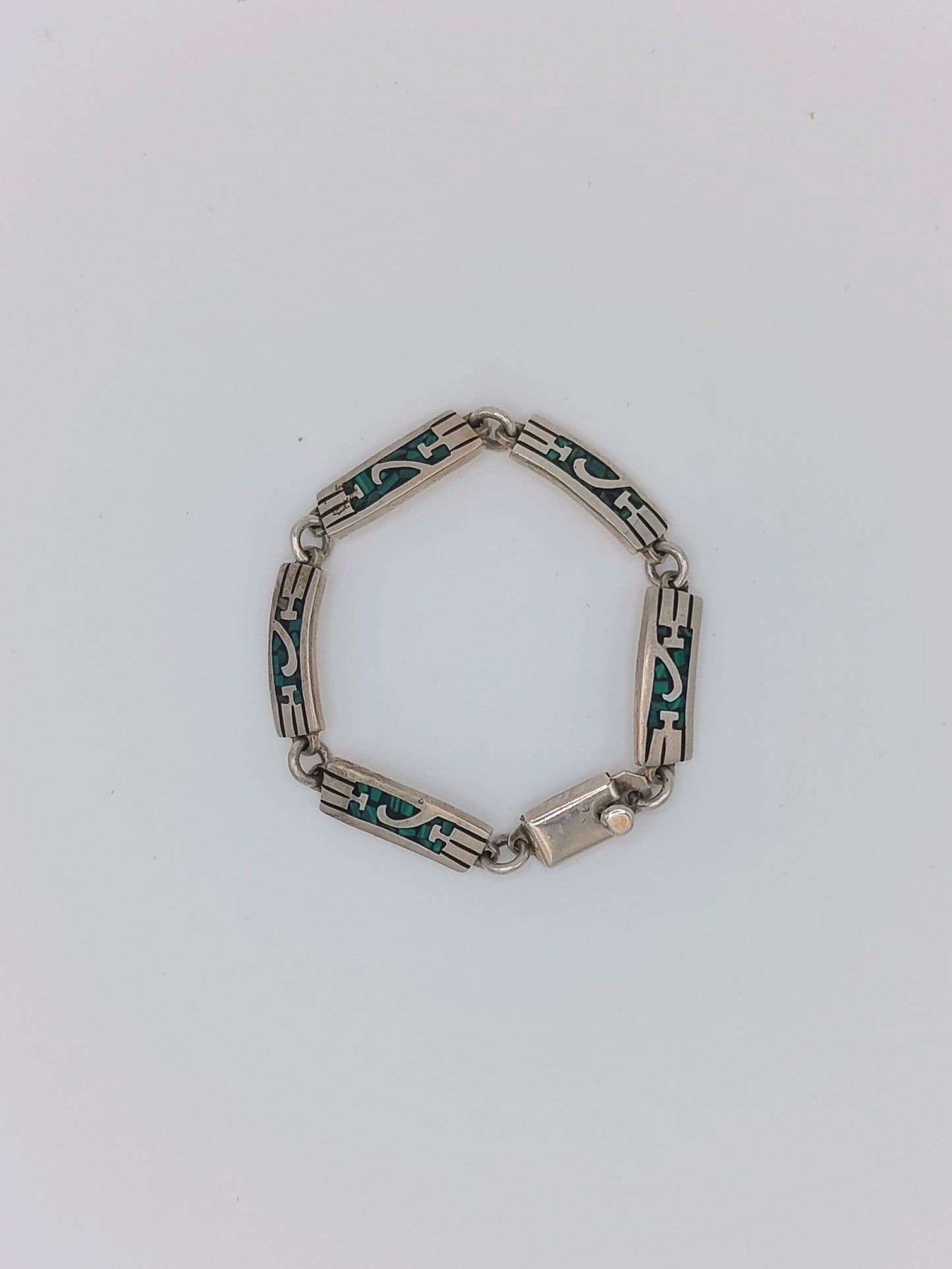 Overhead view of a vintage Mexican sterling silver bracelet with green malachite inlay panels in a geometric