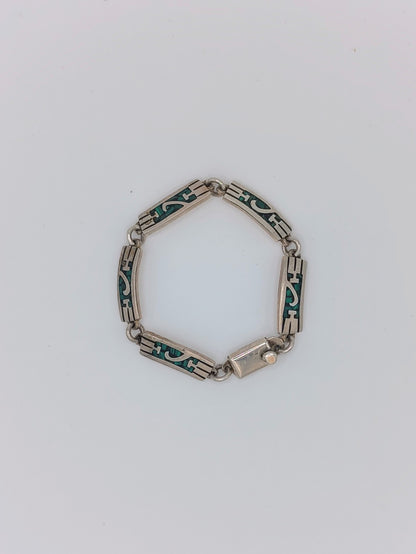 Overhead view of a vintage Mexican sterling silver bracelet with green malachite inlay panels in a geometric