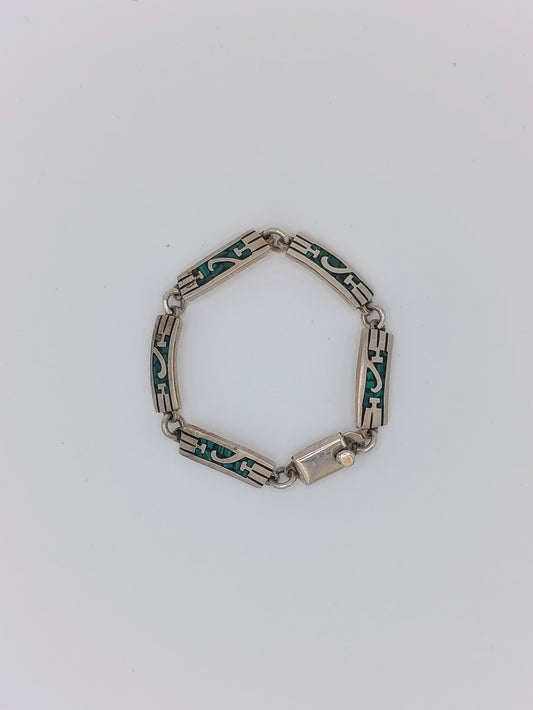 Overhead view of a vintage Mexican sterling silver bracelet with green malachite inlay panels in a geometric