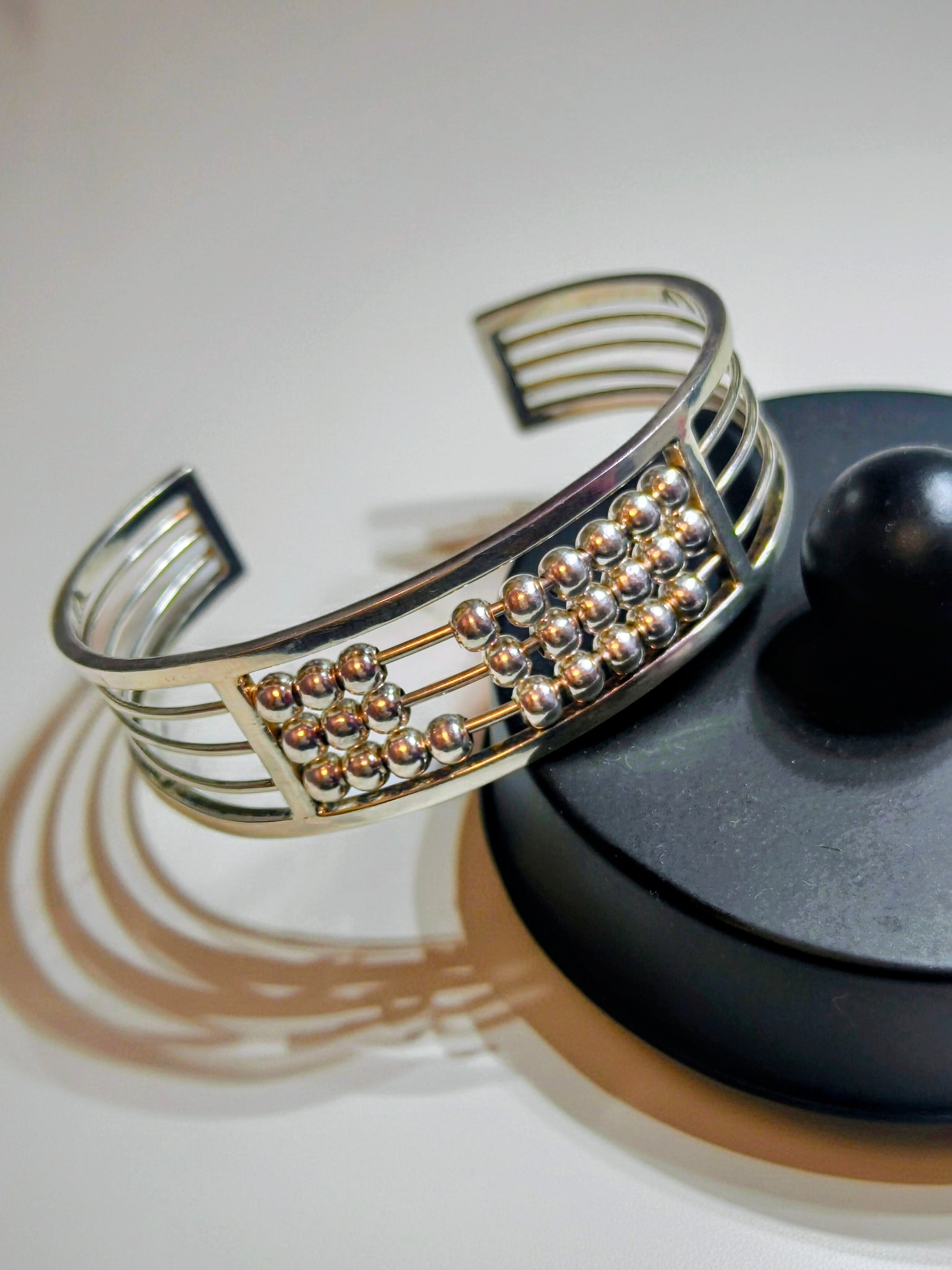 Sterling silver Abacus of Thresholds cuff bracelet with rows of movable silver beads on parallel bars.