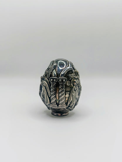 Palm-sized fine silver egg from Greece, richly carved with raised religious icon scenes and darkened recesses.