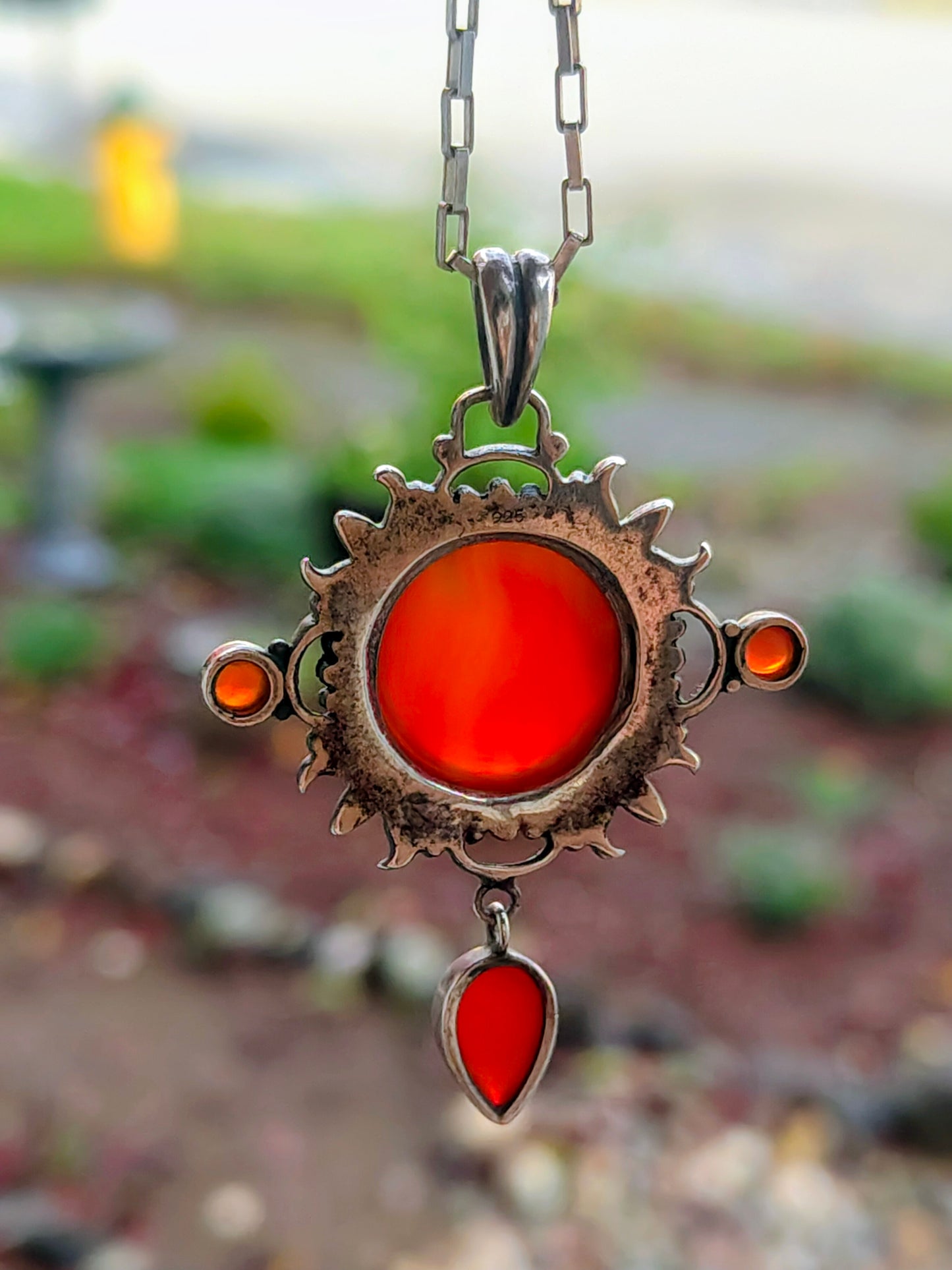 Carnelian Keeper Necklace hanging from a silver chain, glowing orange-red carnelian stones.