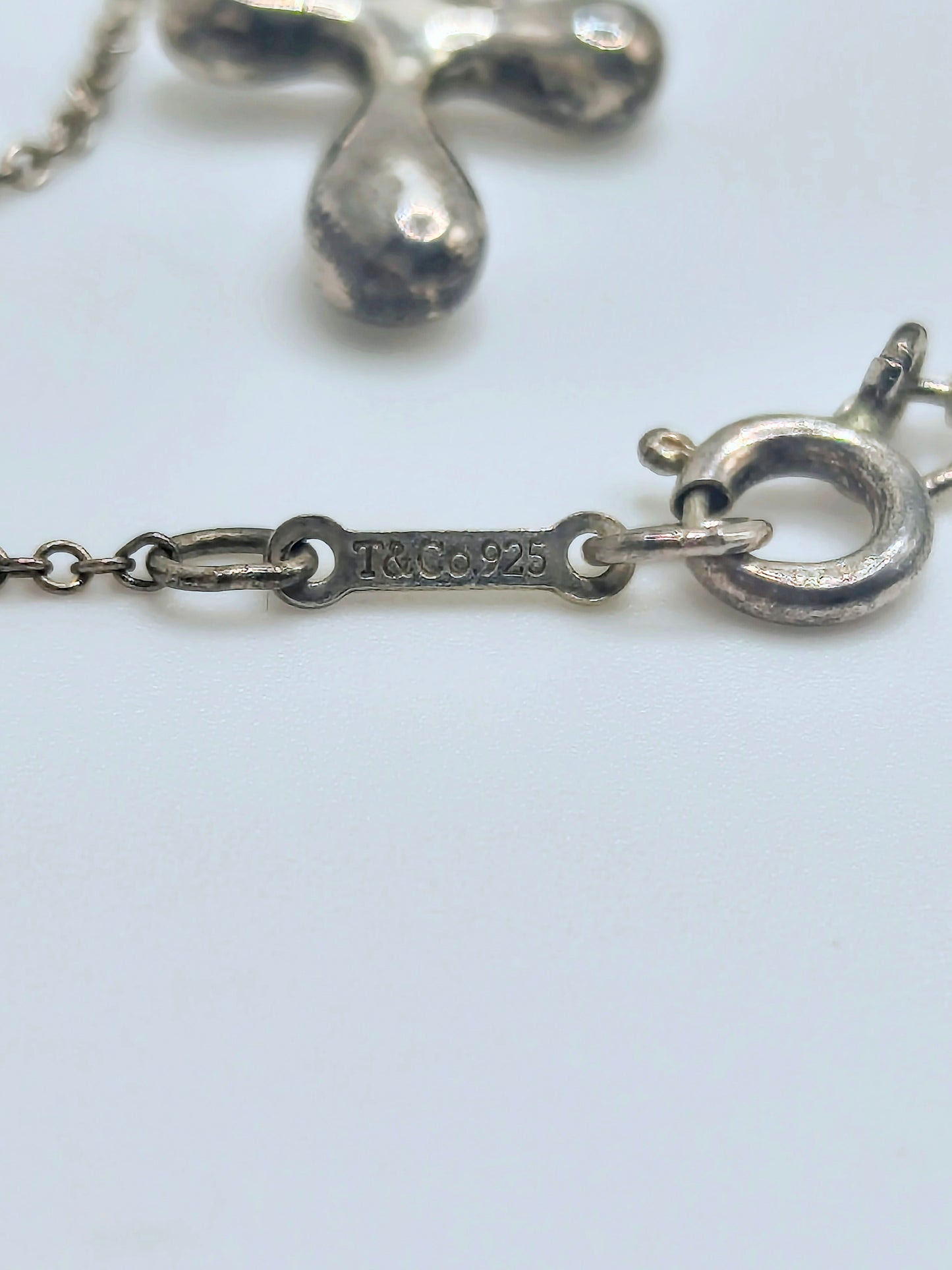 Sterling silver Tiffany & Co. Elsa Peretti teardrop cross pendant hanging from a delicate silver chain.