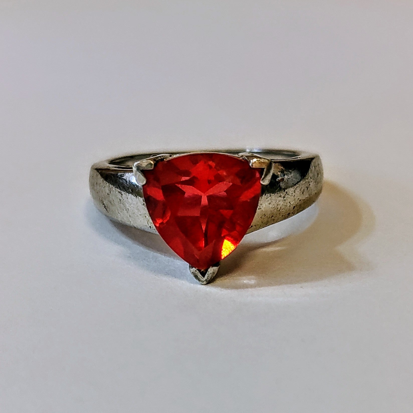 Sterling silver ring featuring a bright triangular-cut red spinel gemstone, displayed on a light background.