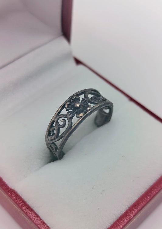 Sterling silver open floral filigree ring with dark patina, adjustable band displayed in a red and white ring box.