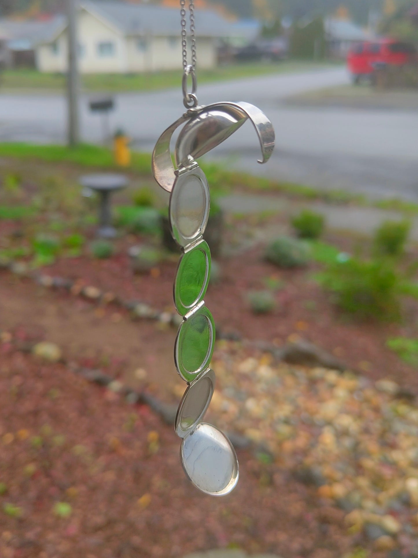 World Within sterling silver orb locket unfolded into six small crescent compartments, laid out on a light surface with chain attached.