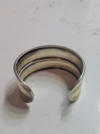 Back view of solid sterling silver horizon-band cuff bracelet with minimal profile, open-ended and slightly oval-shaped.