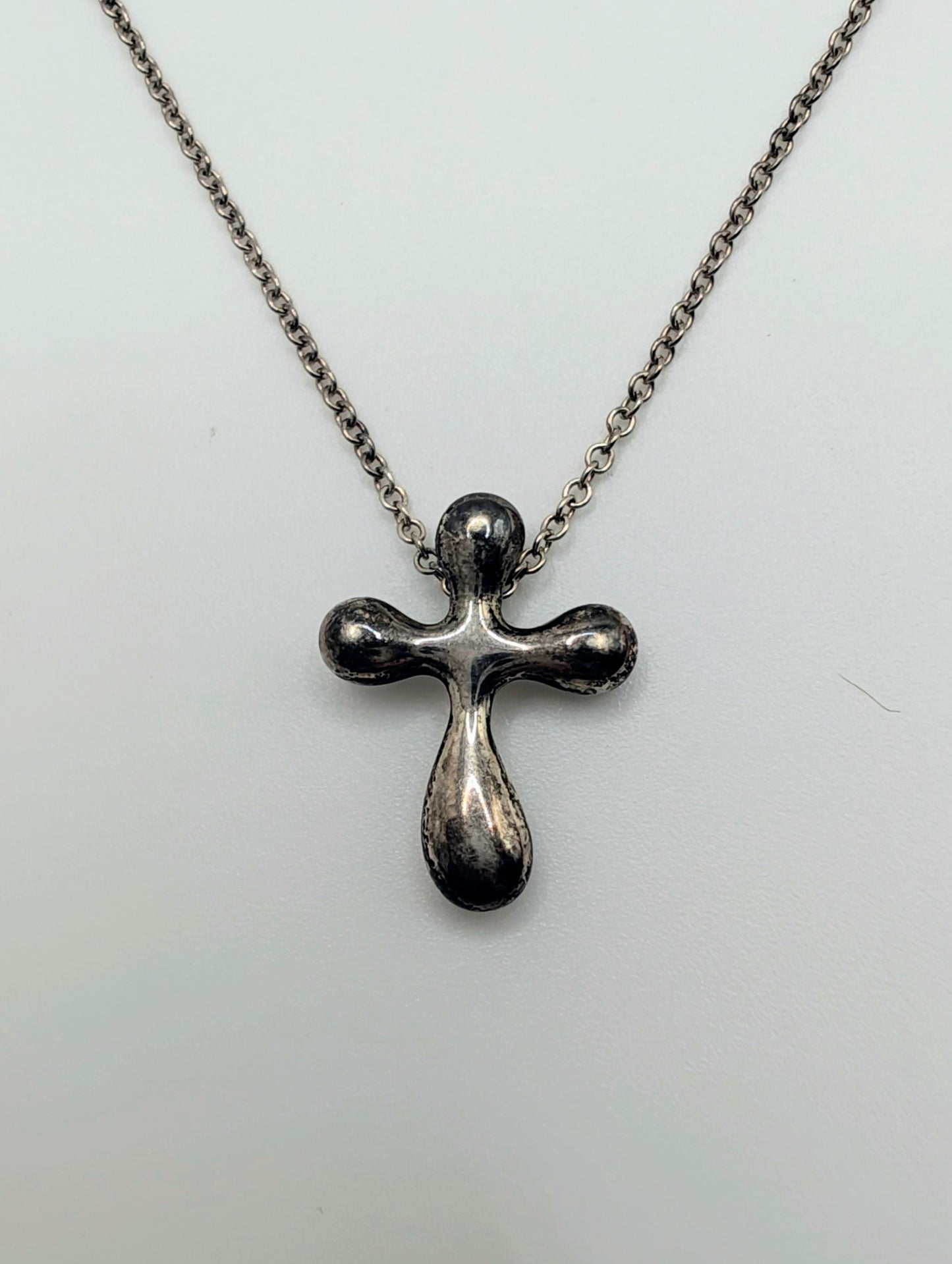 Sterling silver Tiffany & Co. Elsa Peretti teardrop cross pendant hanging from a delicate silver chain.