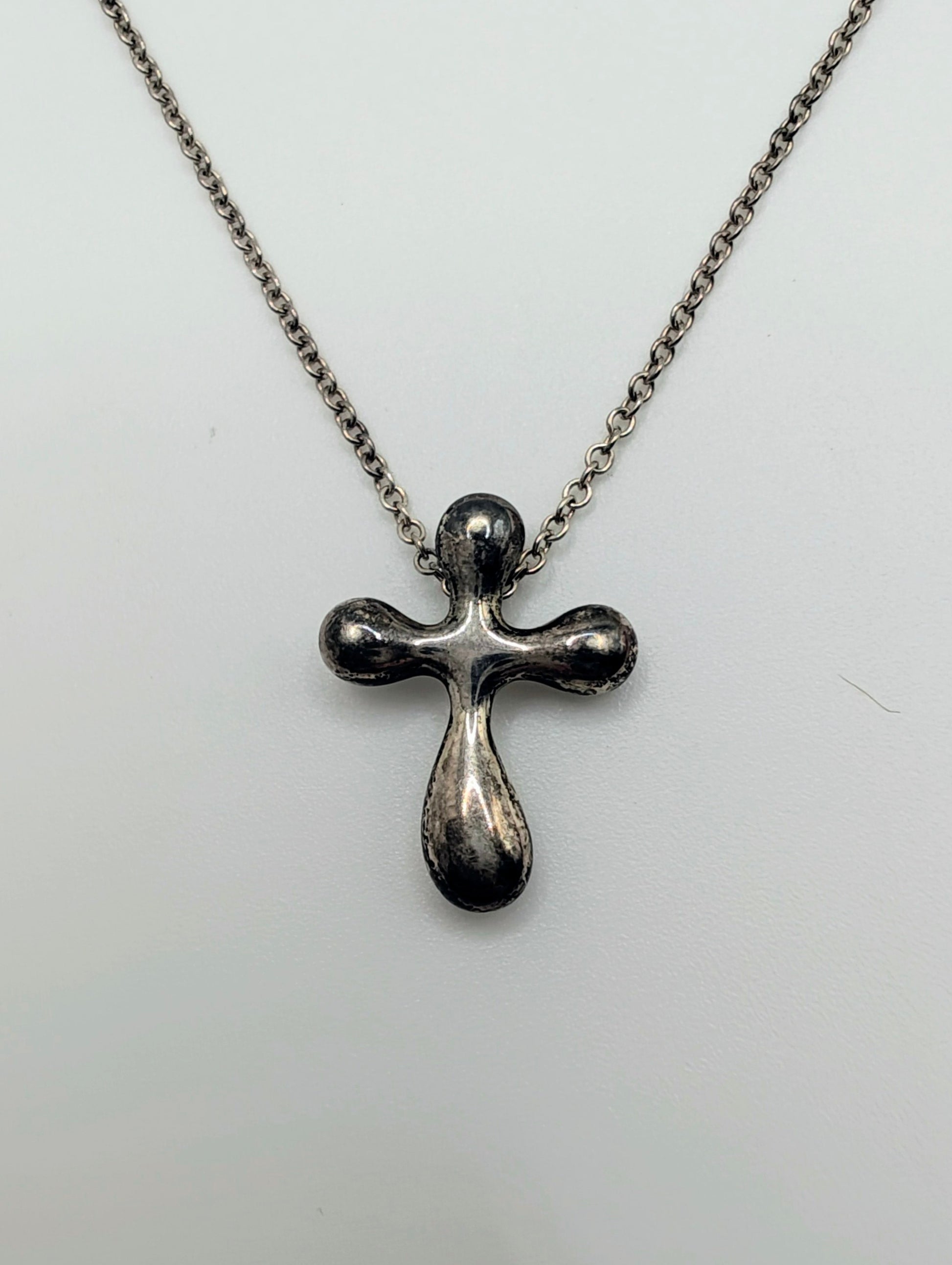 Sterling silver Tiffany & Co. Elsa Peretti teardrop cross pendant hanging from a delicate silver chain.
