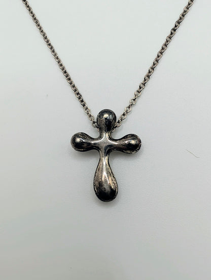 Sterling silver Tiffany & Co. Elsa Peretti teardrop cross pendant hanging from a delicate silver chain.