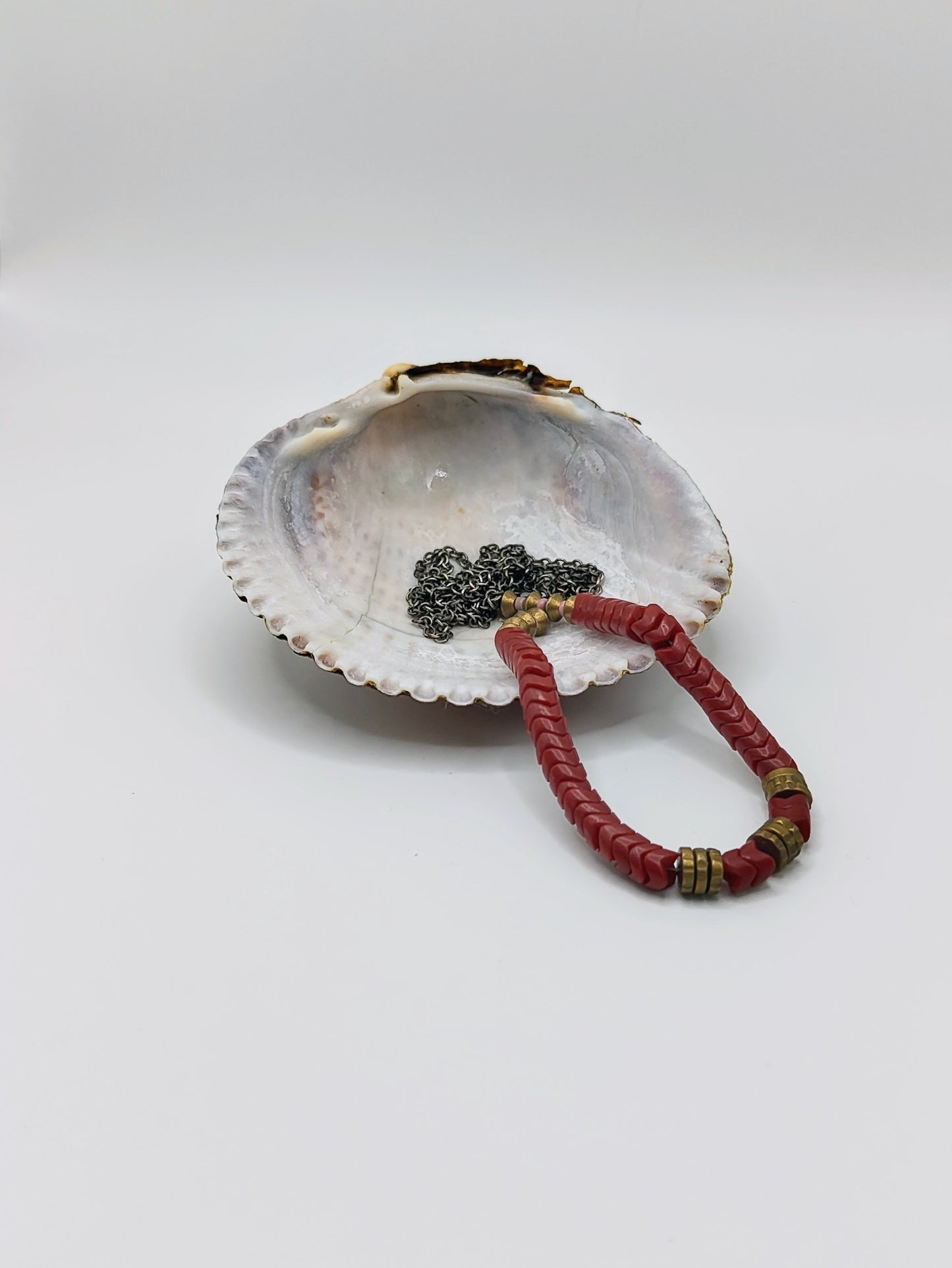 Long mixed-metal necklace with coral-red chevron beads and brass spacers on an oxidized silver chain