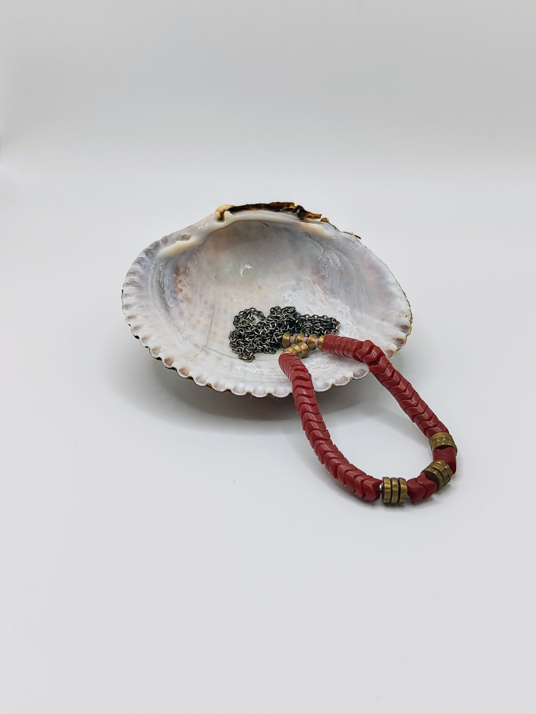 Long mixed-metal necklace with coral-red chevron beads and brass spacers on an oxidized silver chain